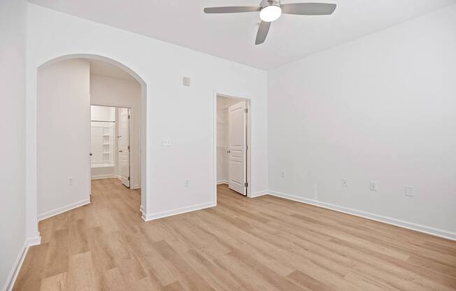 A room with a ceiling fan and wooden flooring.
