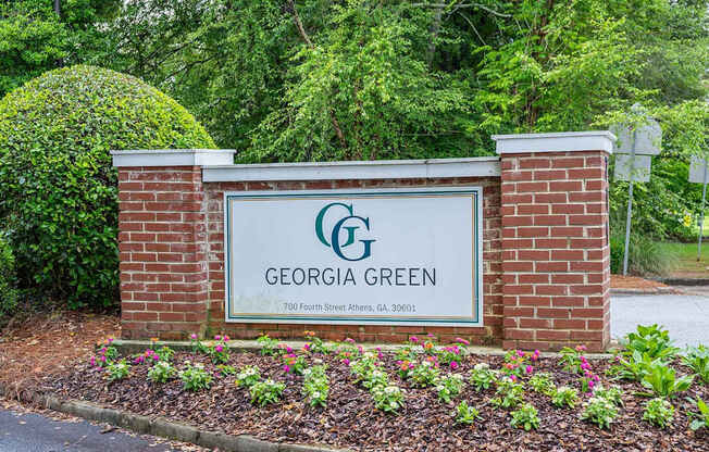 A sign for Georgia Green is displayed in front of a green hedge.