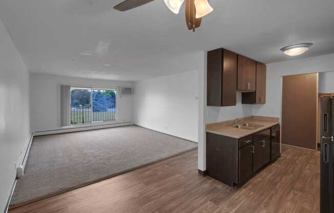 an empty living room and dining room with a ceiling fan