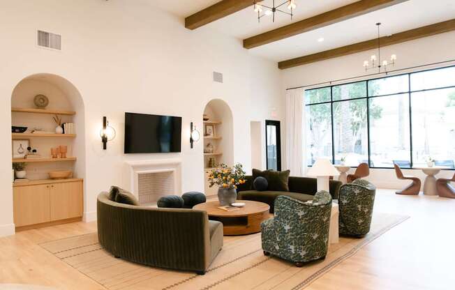 Spacious clubhouse lounge featuring sofas, tables, and natural light.