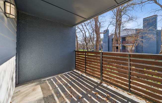 A balcony with a wooden railing and a wall on one side.