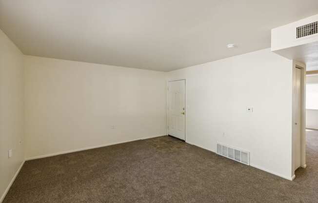 an empty living room with carpet and white walls