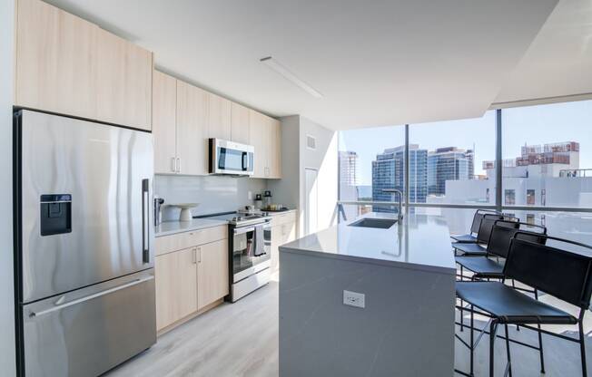 a kitchen with a large island and a stainless steel refrigerator