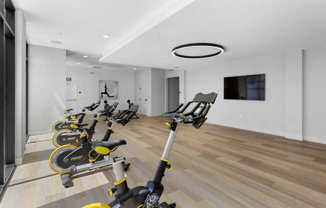 a gym with rows of exercise bikes and a tv on the wall