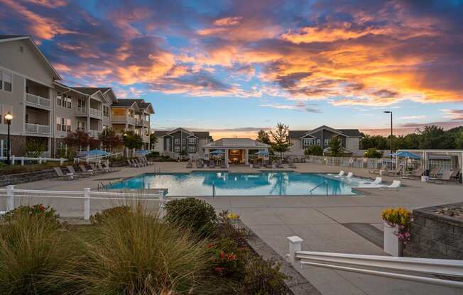 a swimming pool at sunset with apartments in the background