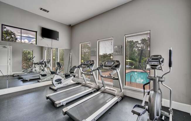 the gym with cardio equipment and windows overlooking the pool