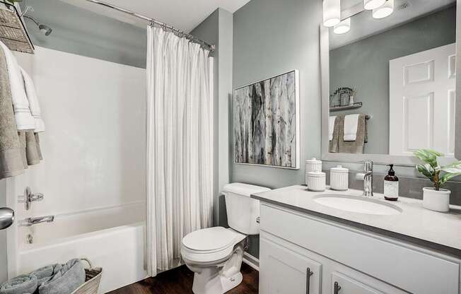 A white toilet is in a bathroom with a white tub and sink.