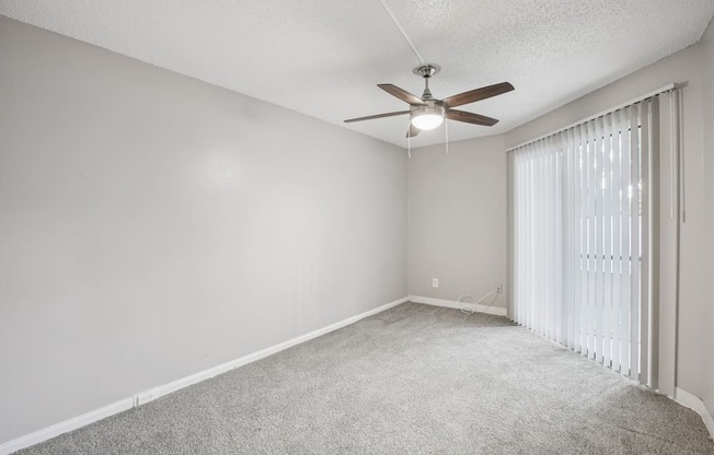 A room with a ceiling fan and carpeted floor.