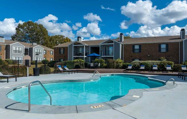 A swimming pool surrounded by a fence and chairs.