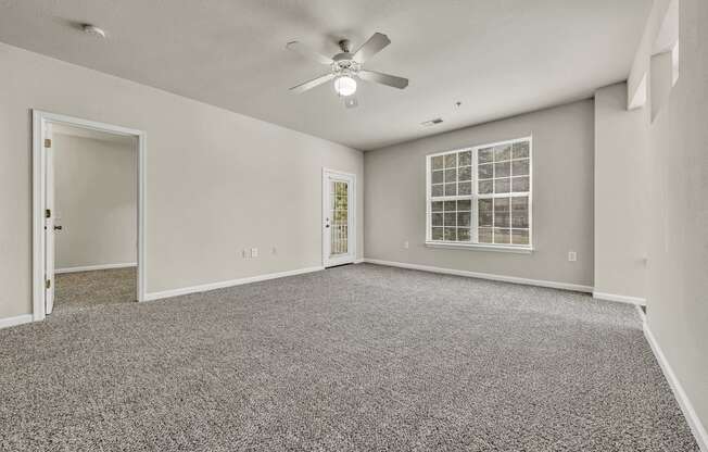 an empty living room with carpet and a ceiling fan