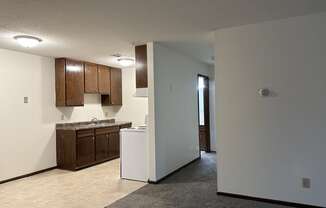 an empty kitchen with brown cabinets and white walls