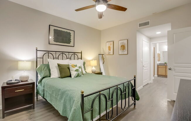 A bedroom with a bed, nightstand, and a ceiling fan.