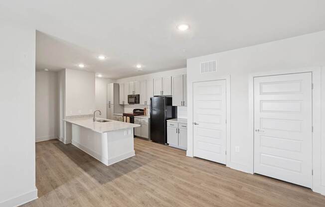 A kitchen with a sink, refrigerator, and cabinets.