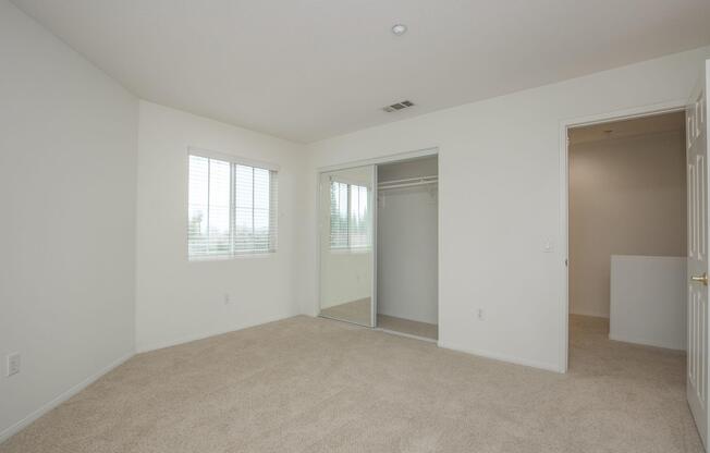 Unfurnished carpeted bedroom with open sliding mirror glass closet doors