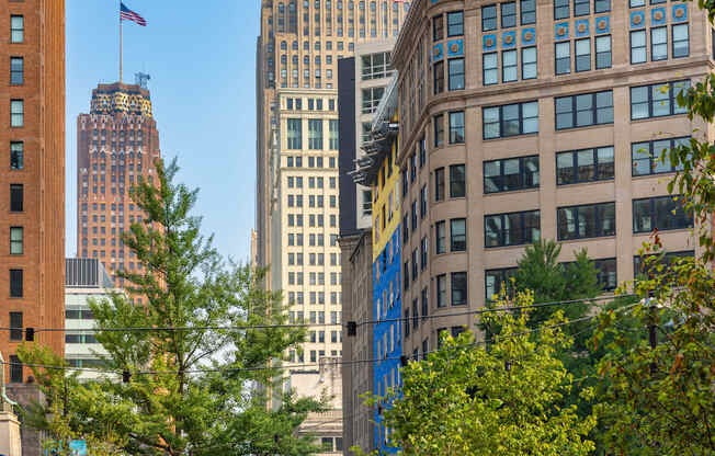 Capitol Park with a walking path and benches in the foreground and a city skyline in the background.