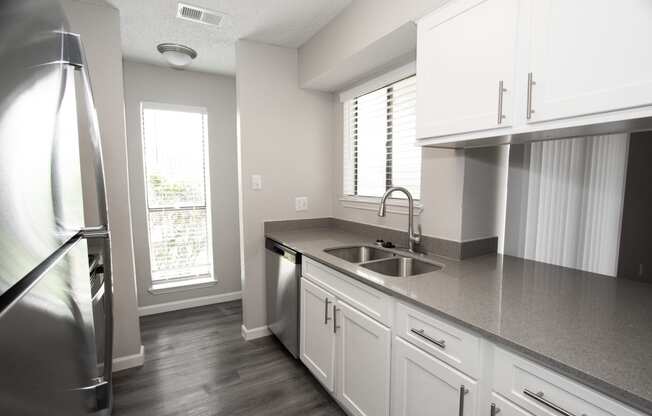 an empty kitchen with white cabinets and a stainless steel sink