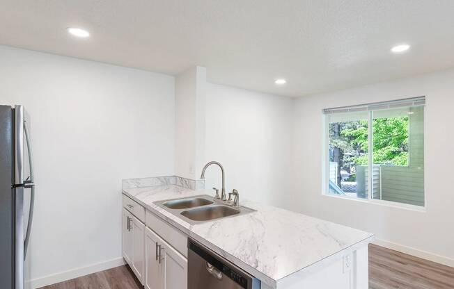 a kitchen with white cabinets and a large window