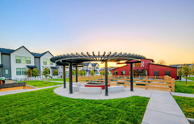 a picnic area with benches and a fire pit at sunset