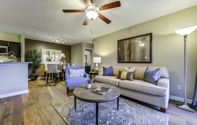 Living room with furniture, a ceiling fan leading to the dining room and kitchen.