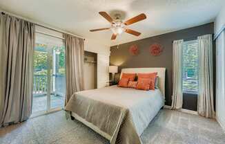 Bedroom with a bed, a ceiling fan, and a sliding glass door.