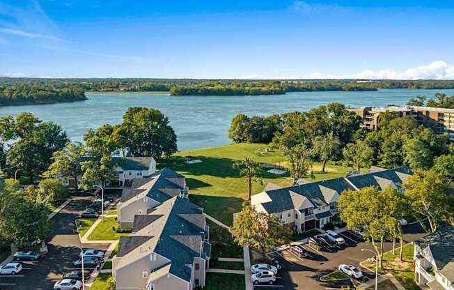 A bird's eye view of a residential area with houses, cars, and a river in the background.