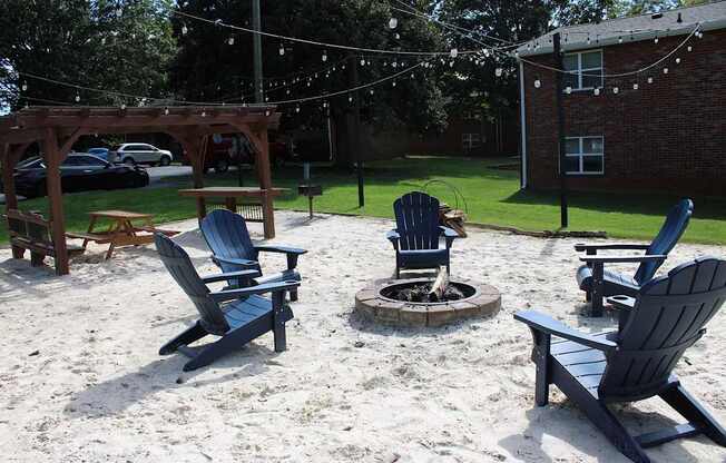 A sandy area with chairs and a fire pit.