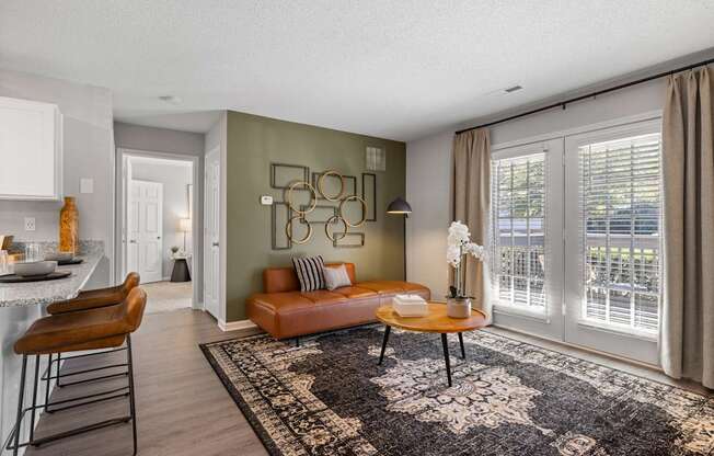 A living room with a brown leather couch and a black and white patterned rug.