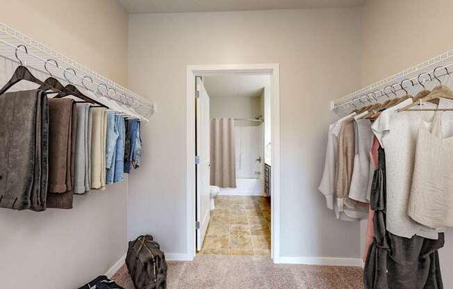 A hallway with clothes hanging on both sides and a bag on the floor.