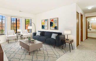 A living room with bay windows and grey couch at Tanglewood Apartments, Oak Creek