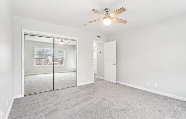 A room with a ceiling fan and carpeted floor.