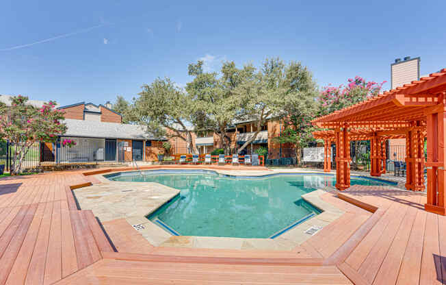 a swimming pool with wooden decking and a poolside cabana and a house