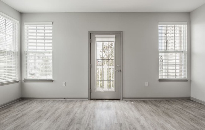 an empty room with a door and three windows