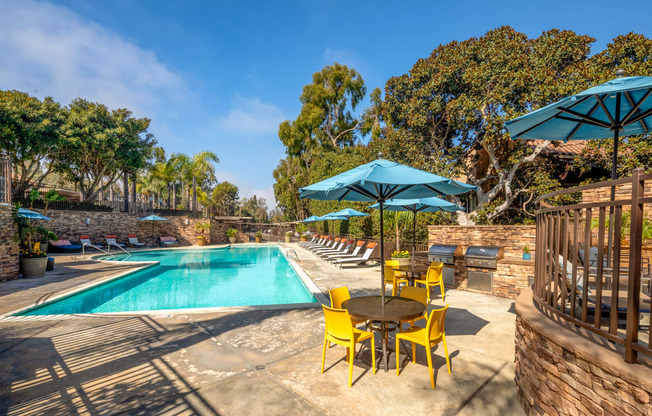 A pool area with a table and chairs and umbrellas.