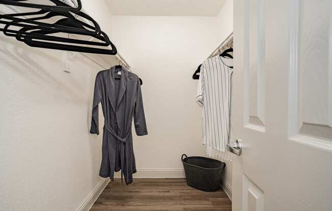 a walk in closet with clothes hanging on the wall