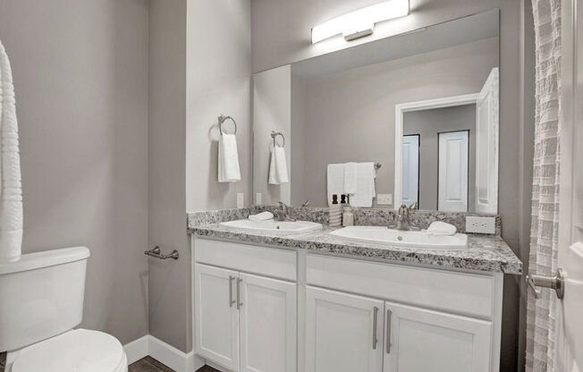 A bathroom with a toilet, sink, and mirror.