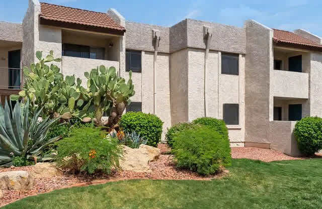 A building with a red tile roof and a well-manicured lawn in front.