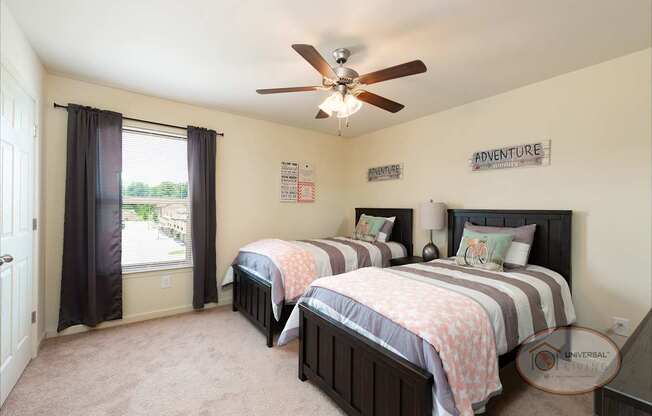 A bedroom with two beds and a ceiling fan.