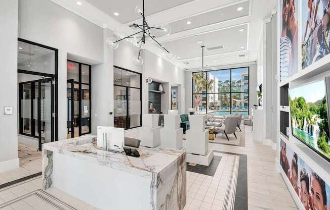 A modern office lobby with a reception desk and a large screen on the wall.