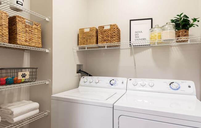a white washer and dryer in a laundry room with baskets on shelves above