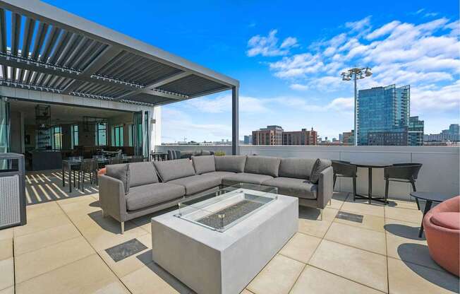 A modern outdoor living space with a large grey sofa and a glass coffee table.