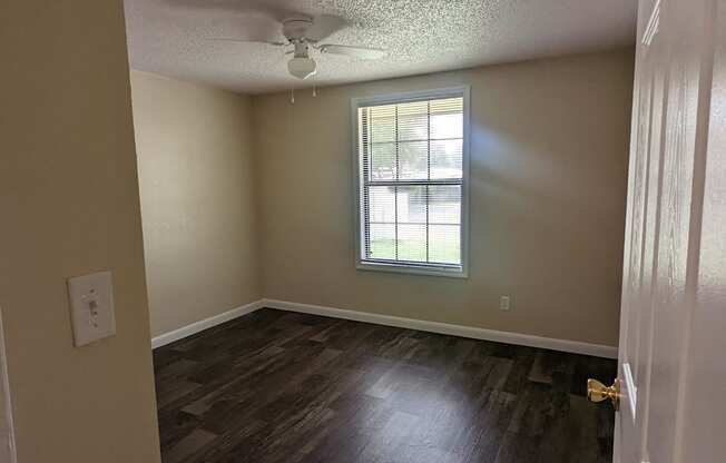 an empty living room with wood floors and a window