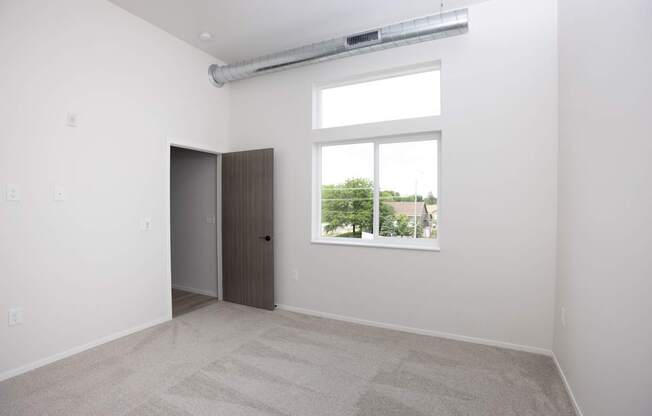 A room with a carpeted floor, a door, and a window.