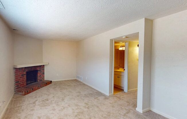 an empty living room with a brick fireplace