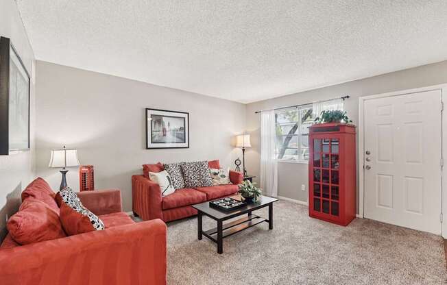 A living room with red couches and a white door.