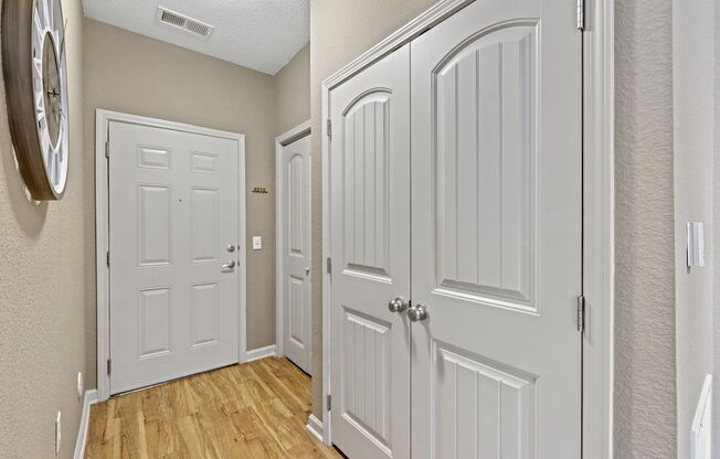 a Fenwyck Manor Apartment home hallway with two doors and a clock on the wall