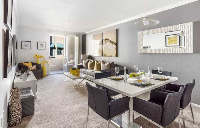 A modern dining room with a white table and grey chairs.