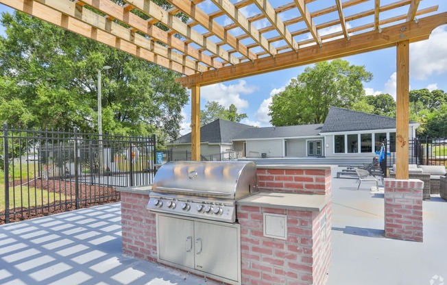 an outdoor kitchen with a grill and a pergola