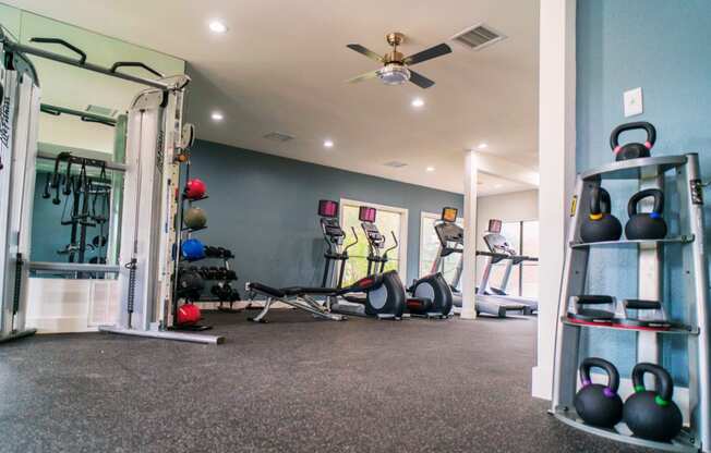 a home gym with weights and a ceiling fan