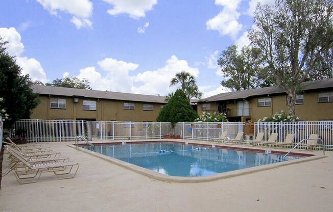 a swimming pool with chairs in front of a building