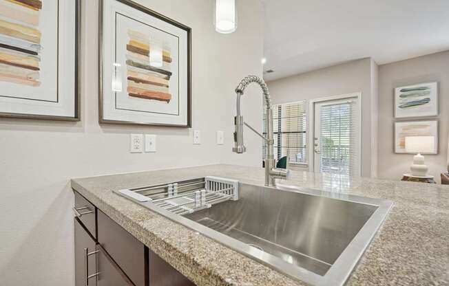 A modern kitchen with a granite countertop and stainless steel sink.